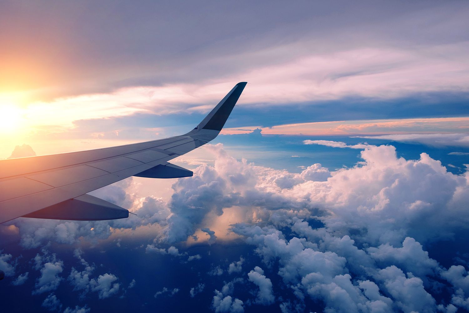 A wing above golden sunset clouds in flight